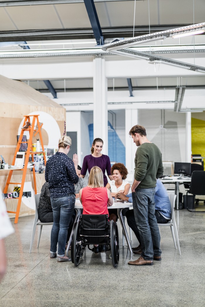 A diverse business team is meeting. Eight colleagues are sharing ideas in a creative office.