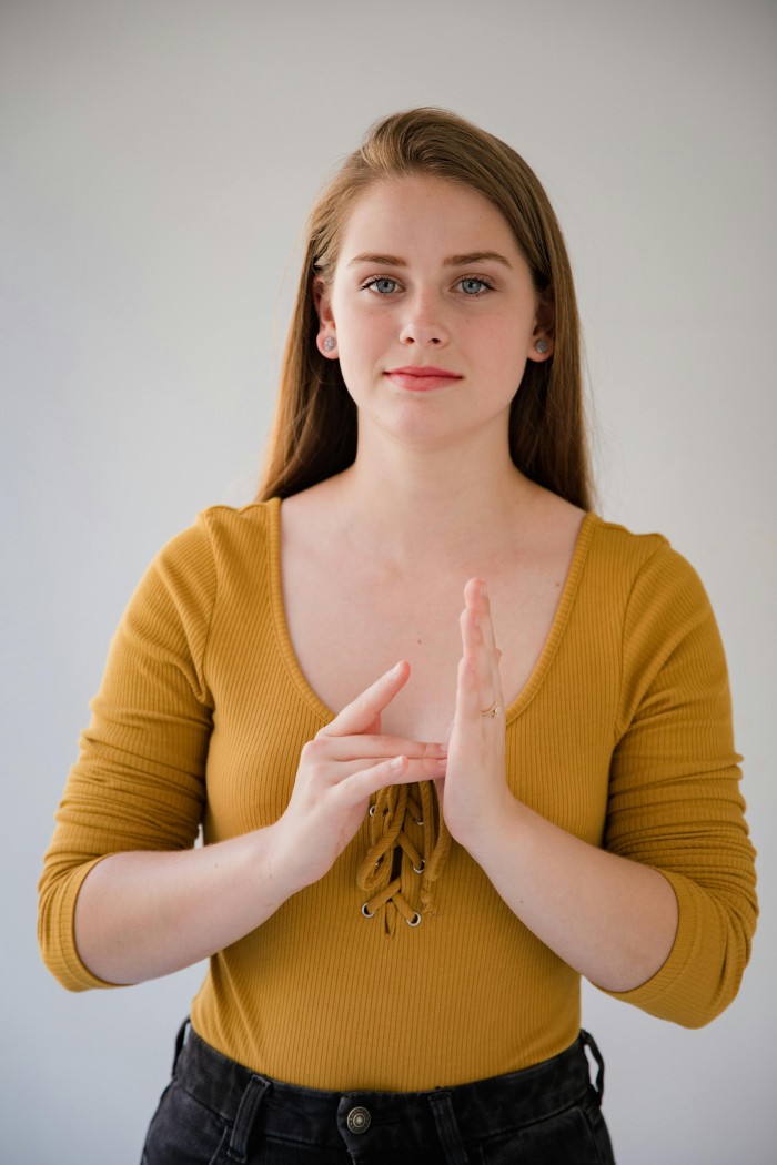 A woman is facing the camera using sign language.
